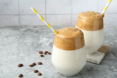 Photo of Delicious dalgona coffee in glasses and beans on grey table, closeup. Space for text