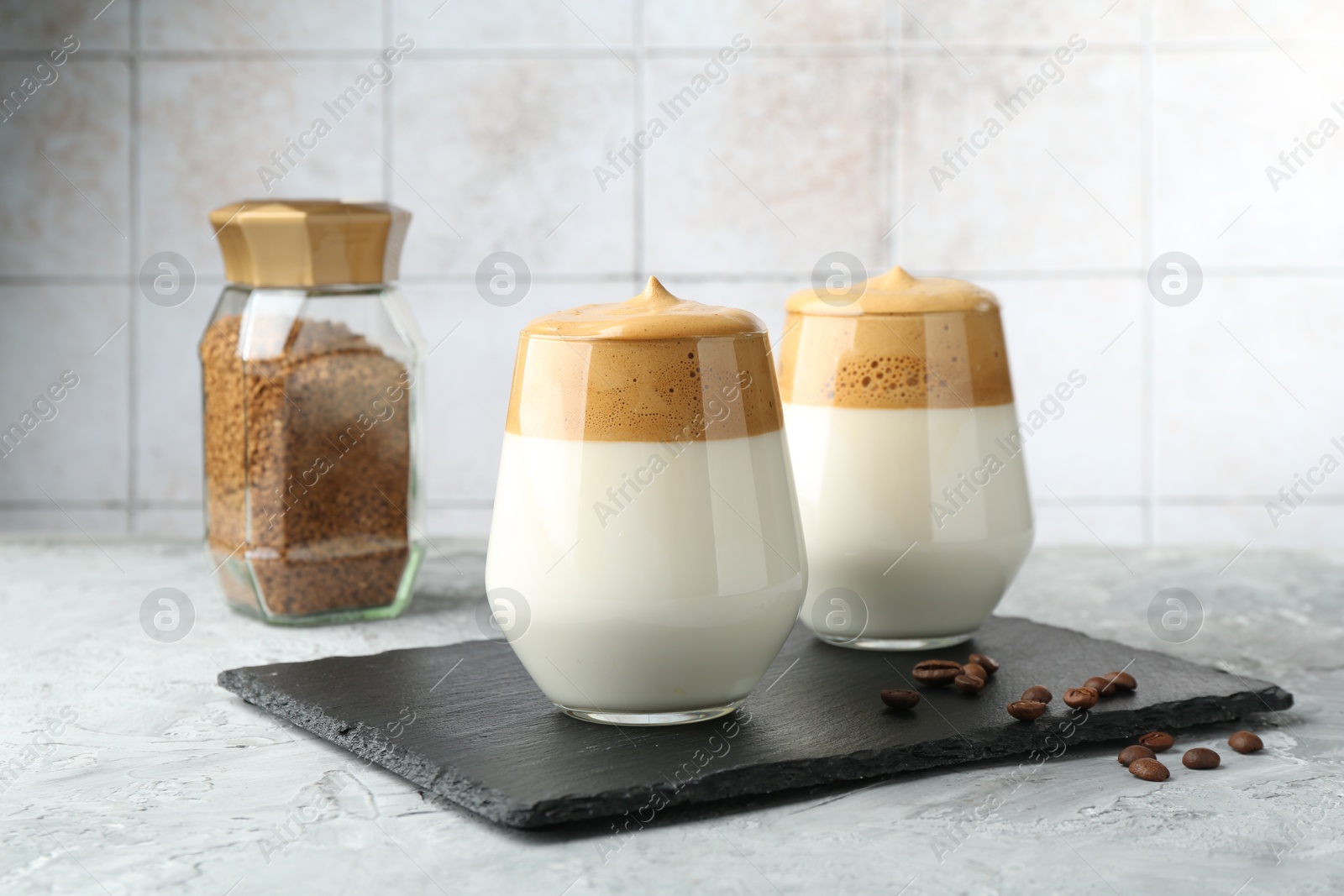 Photo of Delicious dalgona coffee in glasses, beans and granules on grey table