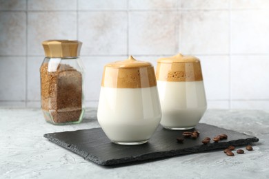 Photo of Delicious dalgona coffee in glasses, beans and granules on grey table