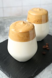 Photo of Delicious dalgona coffee in glasses and beans on grey table, closeup
