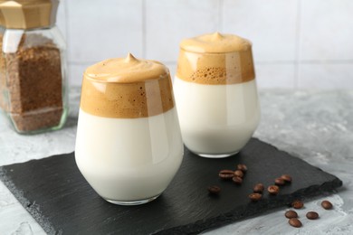 Photo of Delicious dalgona coffee in glasses, beans and granules on grey table, closeup