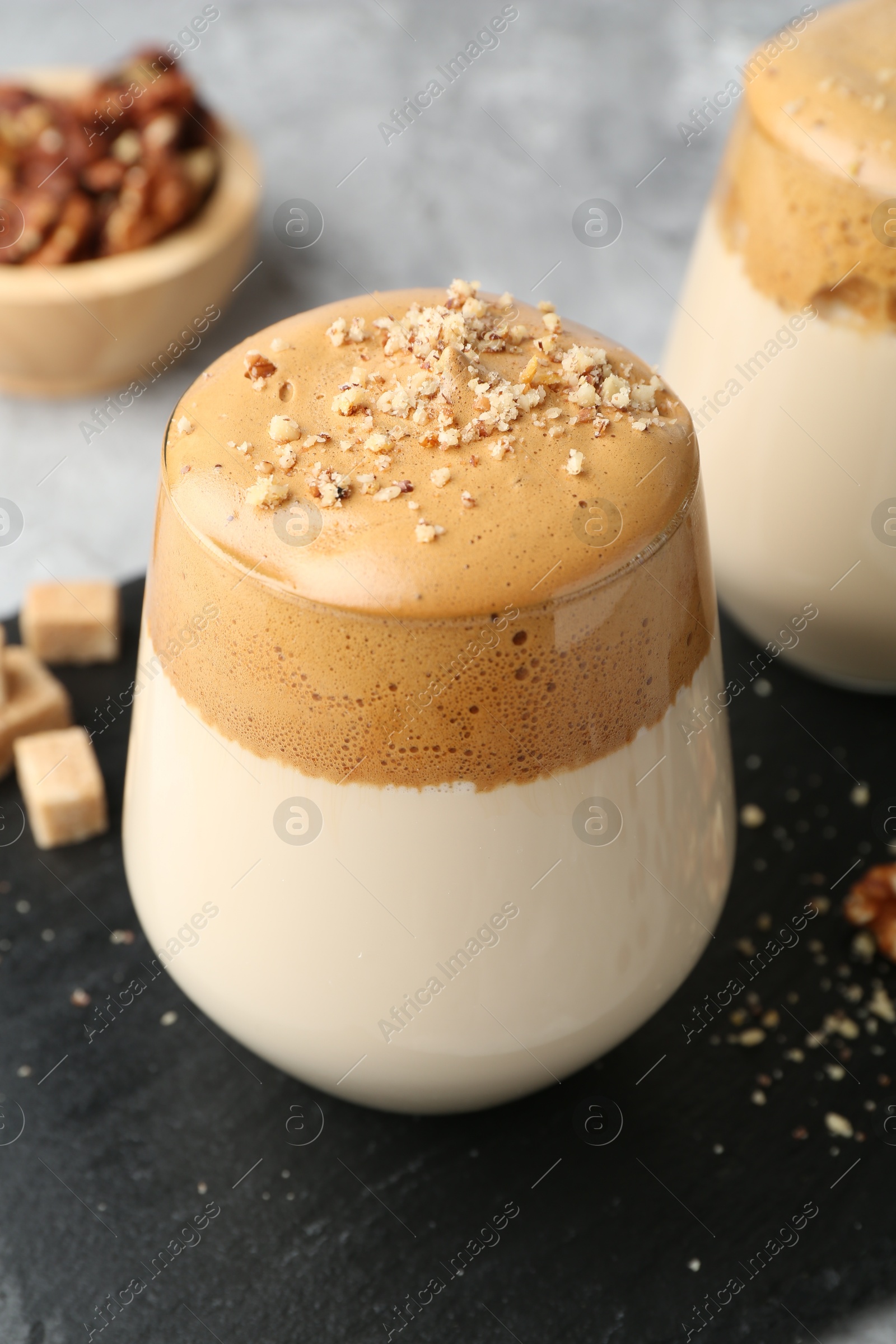 Photo of Delicious dalgona coffee in glasses, brown sugar and walnuts on table, closeup