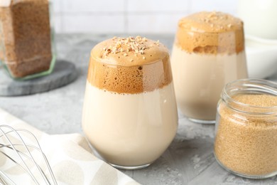 Photo of Delicious dalgona coffee in glasses and brown sugar on grey table, closeup