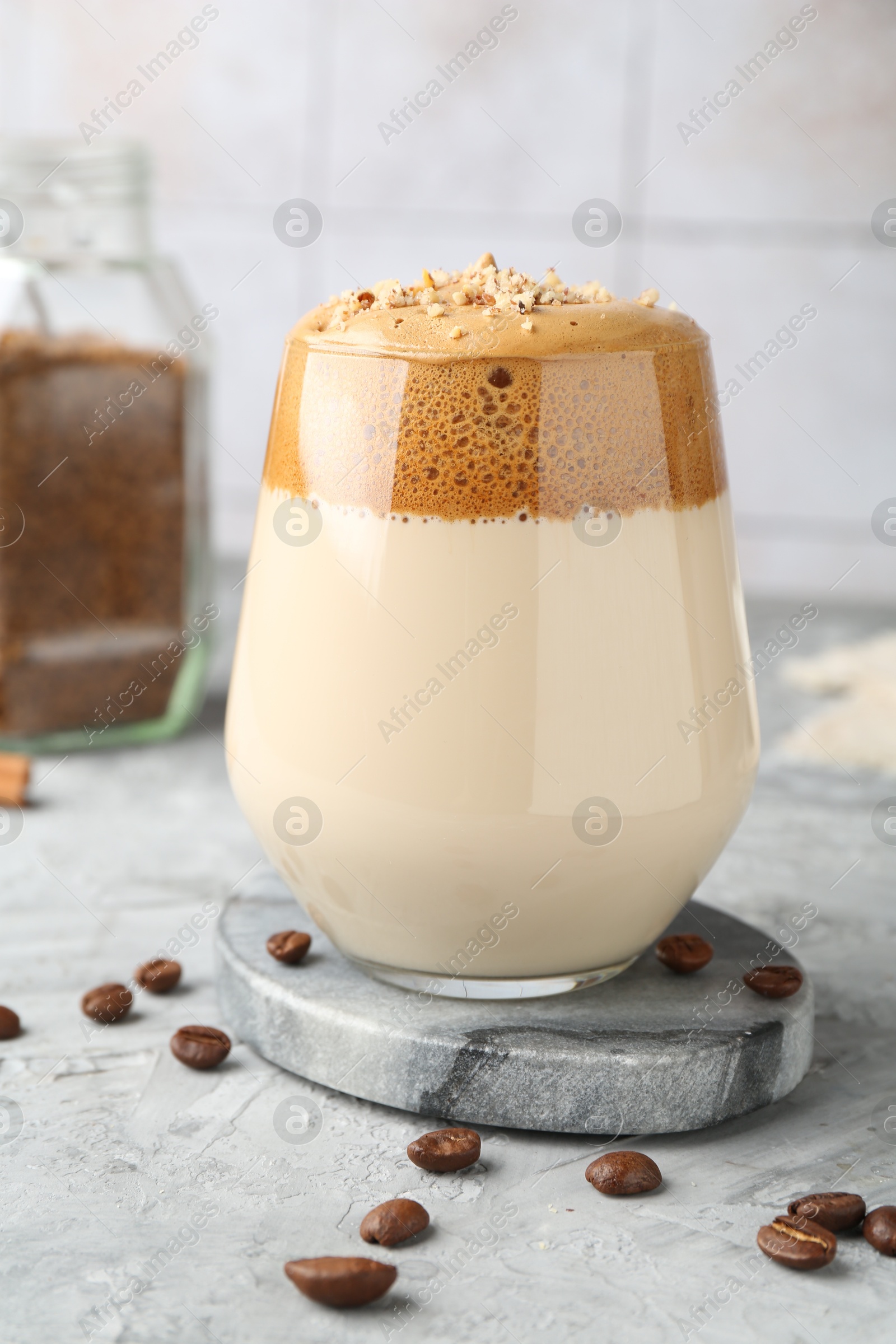 Delicious dalgona coffee in glass, beans and granules on grey table, closeup Photo of Delicious dalgona coffee in glass, beans and granules on grey table, closeup