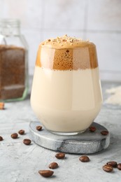 Photo of Delicious dalgona coffee in glass, beans and granules on grey table, closeup
