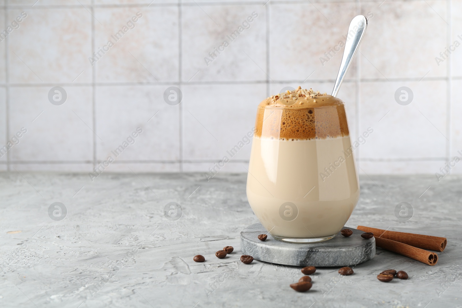 Delicious dalgona coffee in glass, beans and cinnamon on grey table, space for text Photo of Delicious dalgona coffee in glass, beans and cinnamon on grey table, space for text