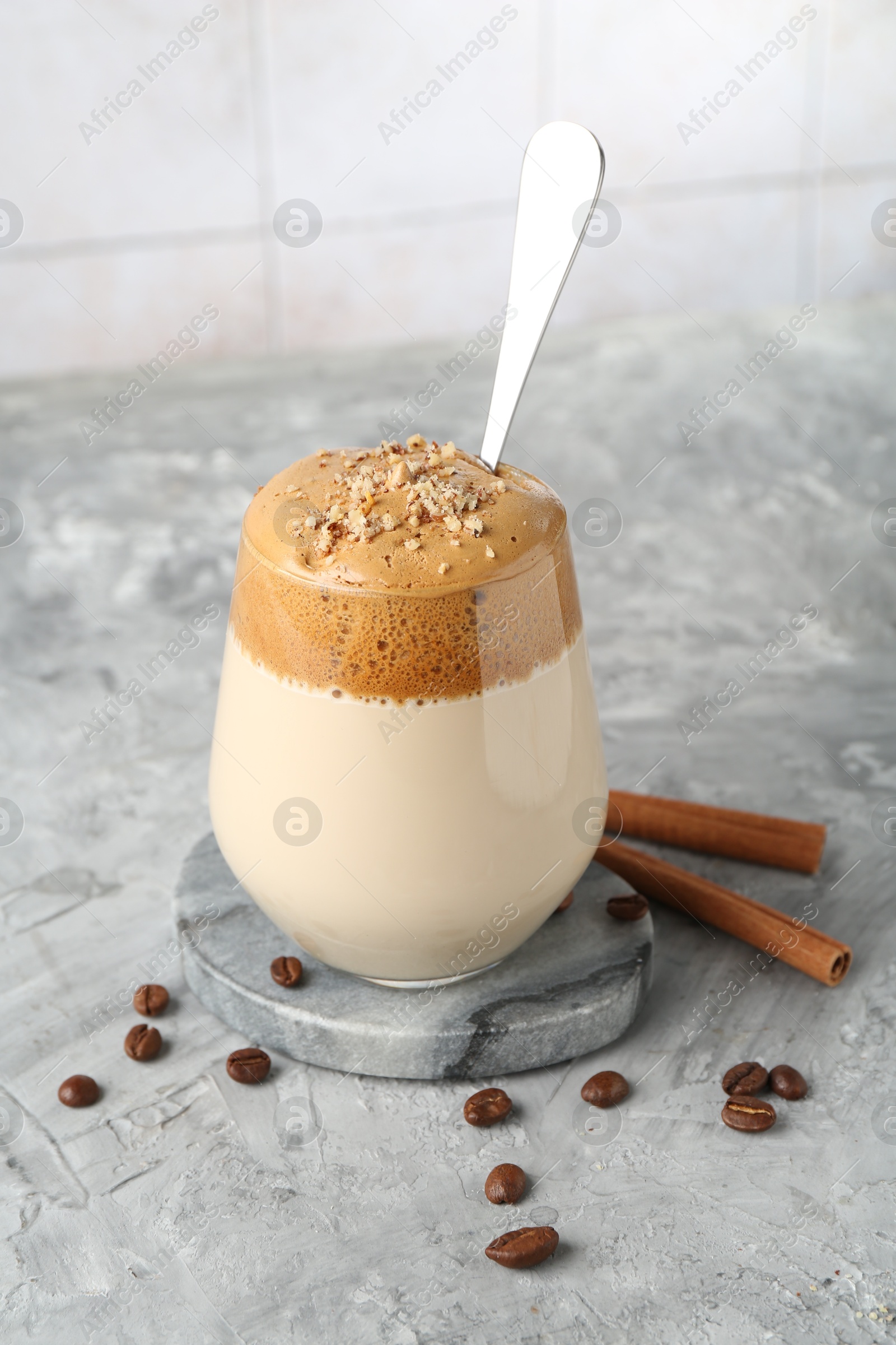 Delicious dalgona coffee in glass, beans and cinnamon on grey table, closeup Photo of Delicious dalgona coffee in glass, beans and cinnamon on grey table, closeup