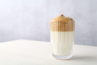 Photo of Delicious dalgona coffee in glass on light table, space for text
