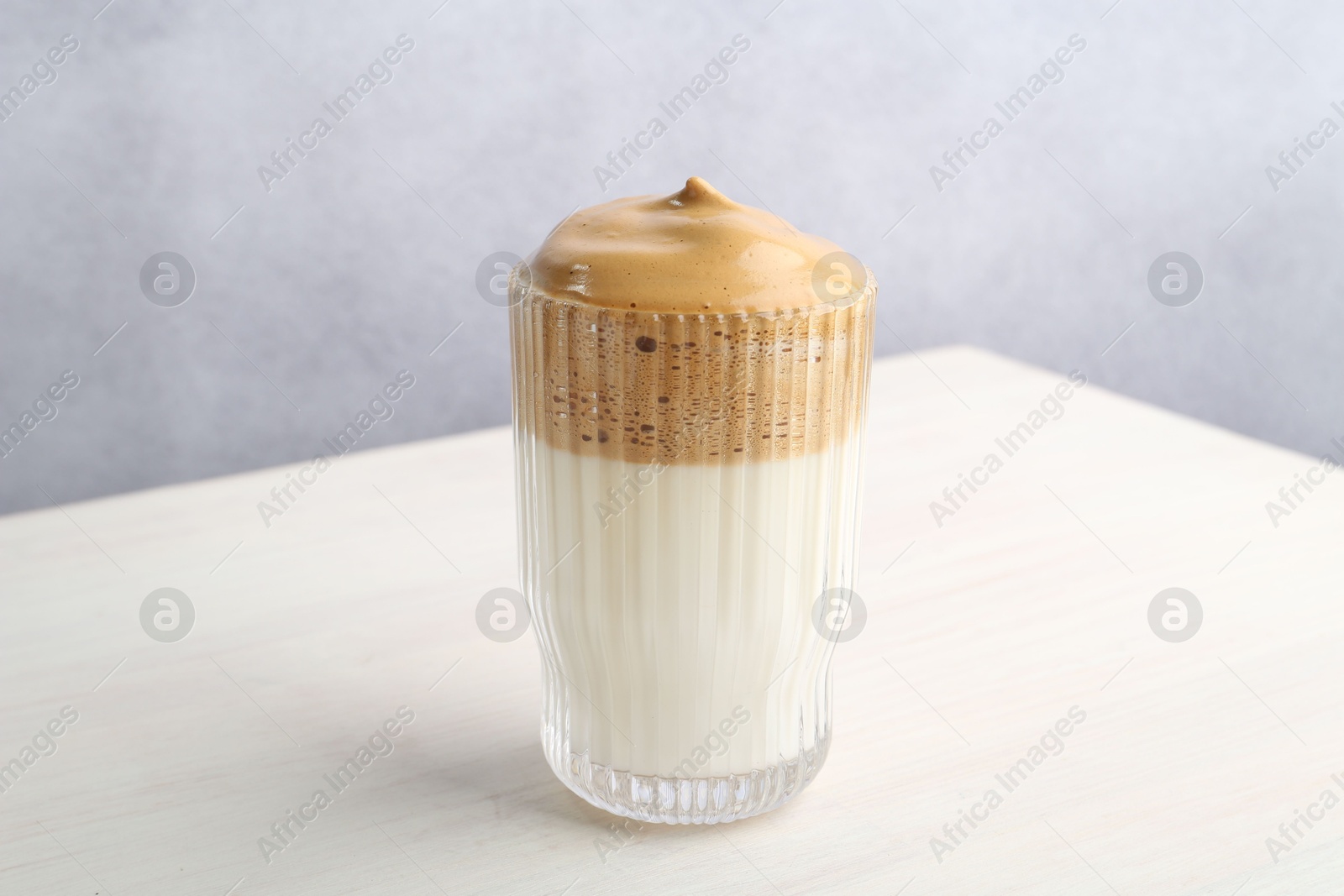 Delicious dalgona coffee in glass on light table, closeup Photo of Delicious dalgona coffee in glass on light table, closeup