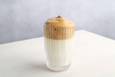 Photo of Delicious dalgona coffee in glass on light table, closeup