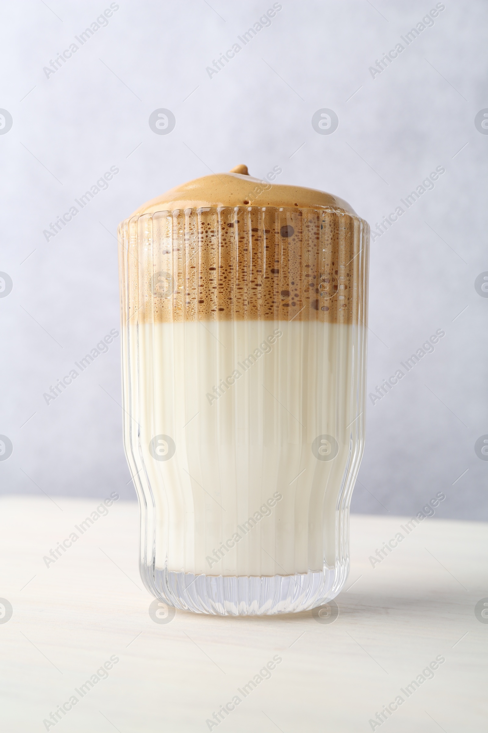 Delicious dalgona coffee in glass on light table, low angle view Photo of Delicious dalgona coffee in glass on light table, low angle view
