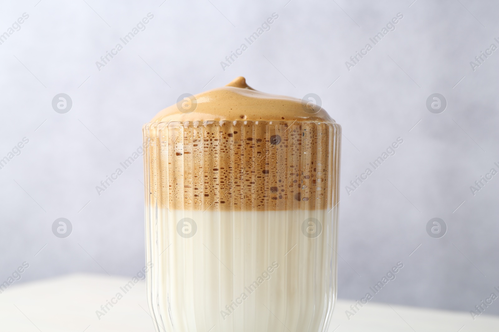 Photo of Delicious dalgona coffee in glass on blurred background, closeup