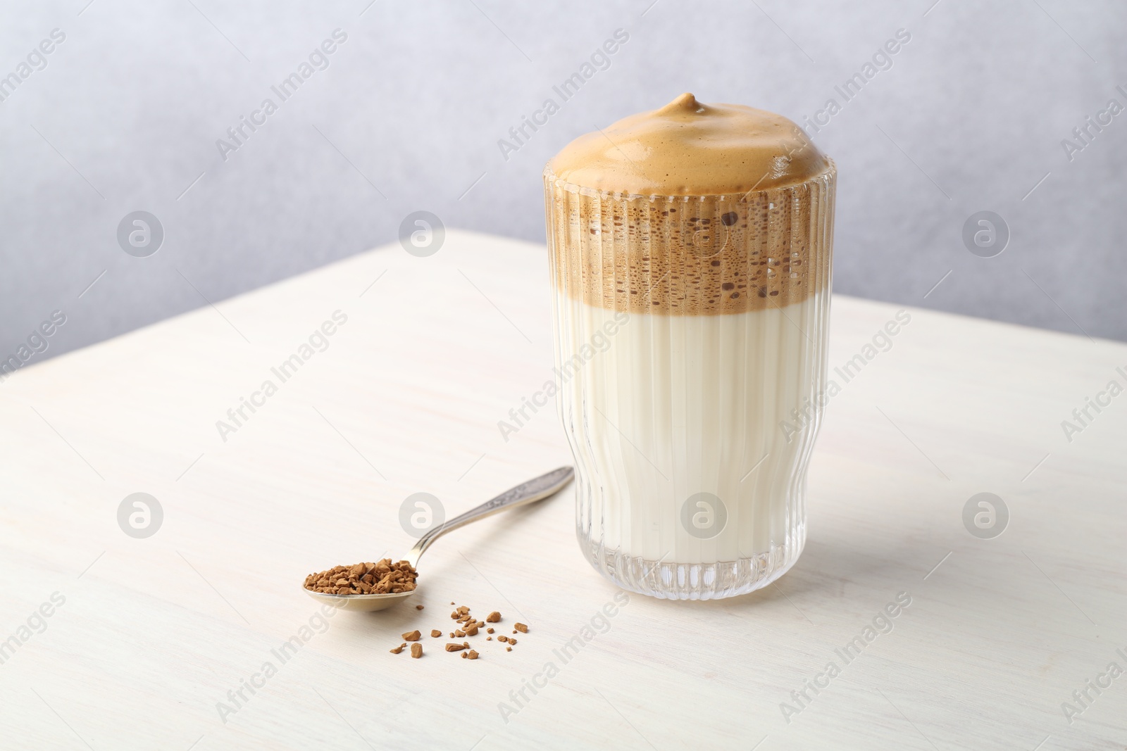 Delicious dalgona coffee in glass and granules on light table, closeup. Space for text Photo of Delicious dalgona coffee in glass and granules on light table, closeup. Space for text