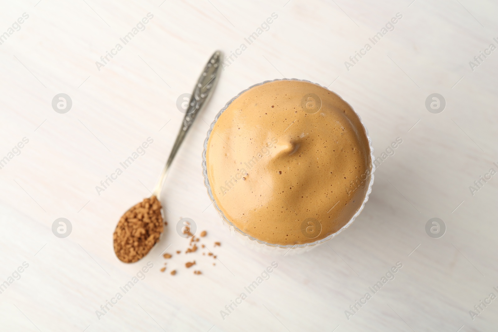 Delicious dalgona coffee in glass and granules on light table, flat lay Photo of Delicious dalgona coffee in glass and granules on light table, flat lay