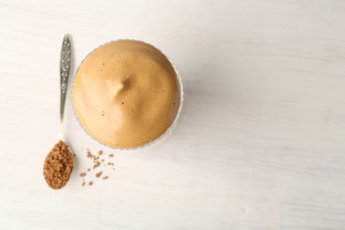 Photo of Delicious dalgona coffee in glass and granules on light table, flat lay. Space for text