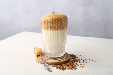 Photo of Delicious dalgona coffee in glass and granules on light table