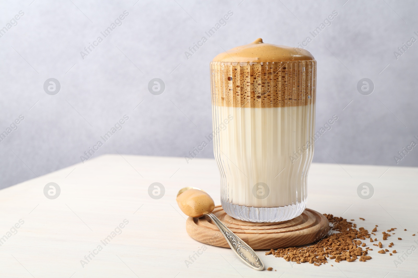 Delicious dalgona coffee in glass and granules on light table, closeup. Space for text Photo of Delicious dalgona coffee in glass and granules on light table, closeup. Space for text