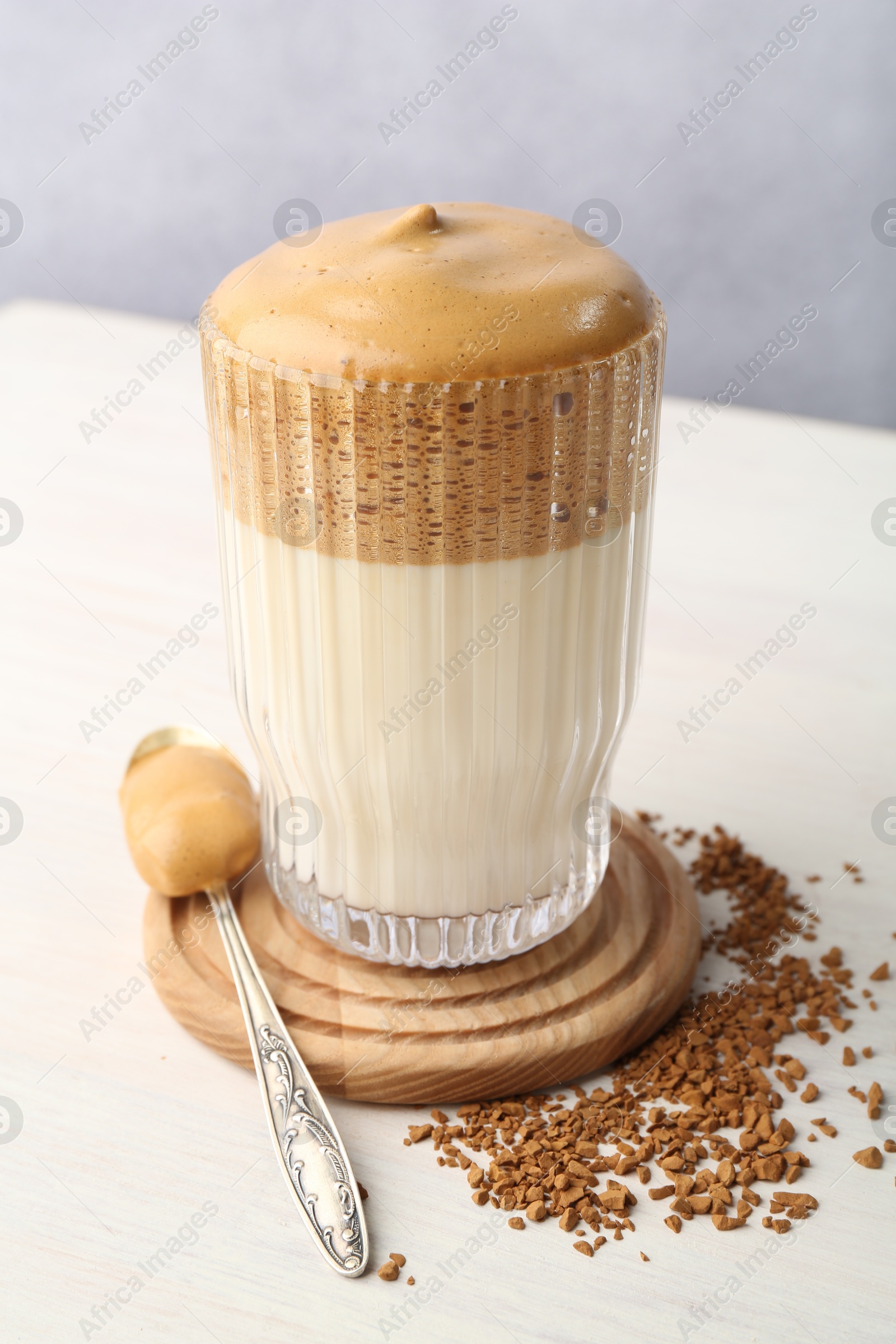 Delicious dalgona coffee in glass and granules on light table, closeup Photo of Delicious dalgona coffee in glass and granules on light table, closeup