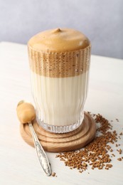 Photo of Delicious dalgona coffee in glass and granules on light table, closeup