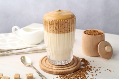 Photo of Delicious dalgona coffee in glass, granules and brown sugar on light table, closeup