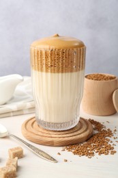 Photo of Delicious dalgona coffee in glass, granules and brown sugar on light table, closeup