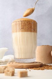 Photo of Taking cream from delicious dalgona coffee at light table, low angle view