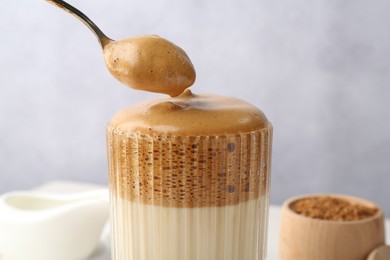 Photo of Taking cream from delicious dalgona coffee on blurred background, closeup