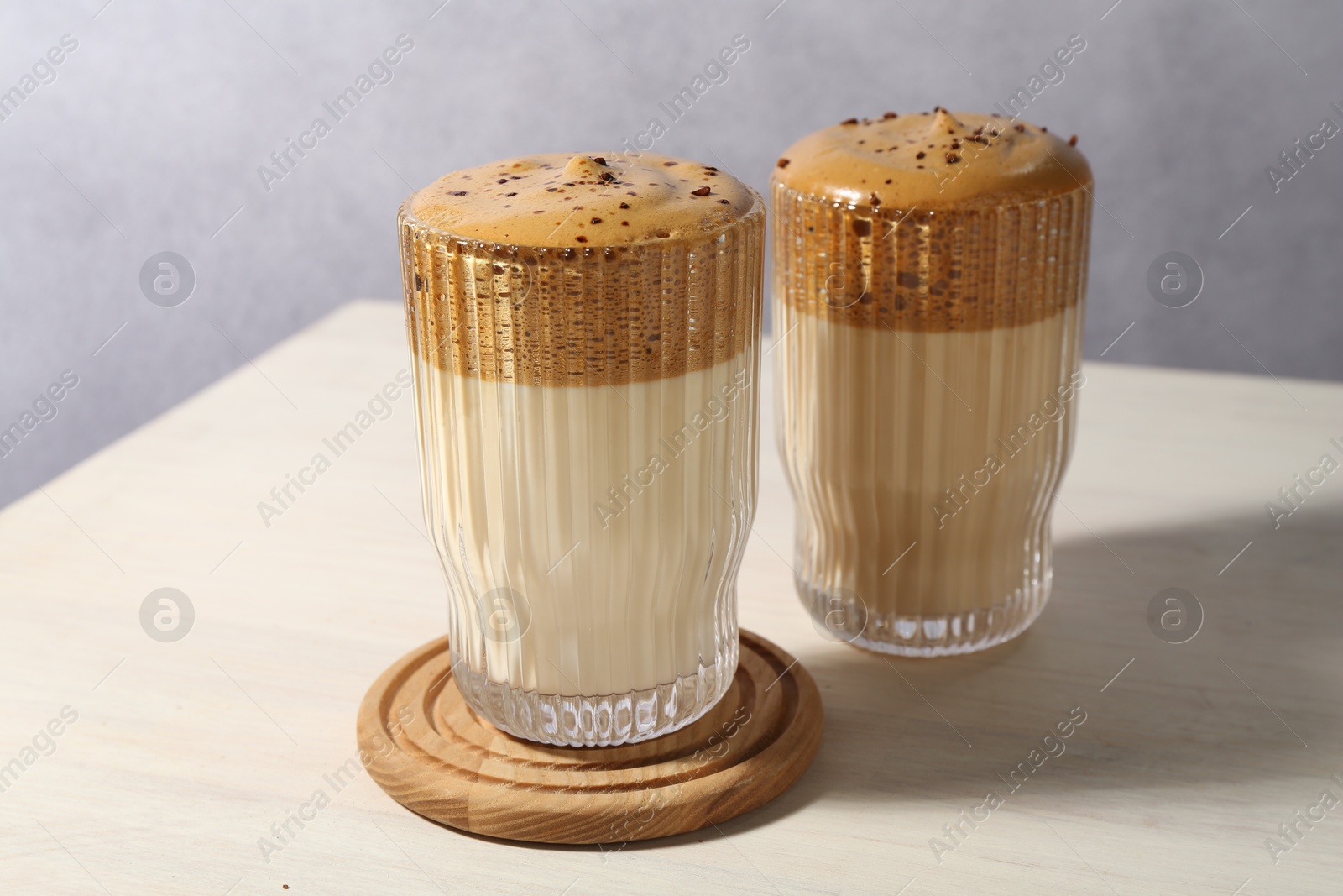 Photo of Delicious dalgona coffee in glasses on light table, closeup