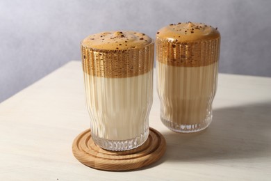 Photo of Delicious dalgona coffee in glasses on light table, closeup