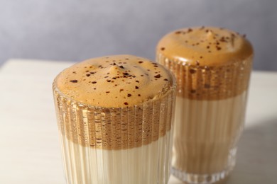 Photo of Delicious dalgona coffee in glasses on light table, closeup