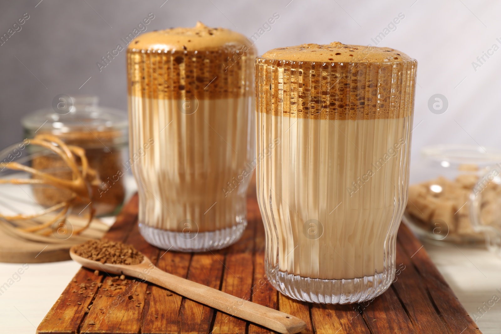 Delicious dalgona coffee in glasses, whisk, brown sugar and granules on table, closeup Photo of Delicious dalgona coffee in glasses, whisk, brown sugar and granules on table, closeup