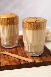 Photo of Delicious dalgona coffee in glasses and granules on light table, closeup