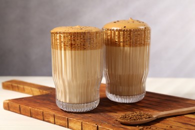 Photo of Delicious dalgona coffee in glasses and granules on light table, closeup