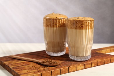 Photo of Delicious dalgona coffee in glasses and granules on light table, closeup