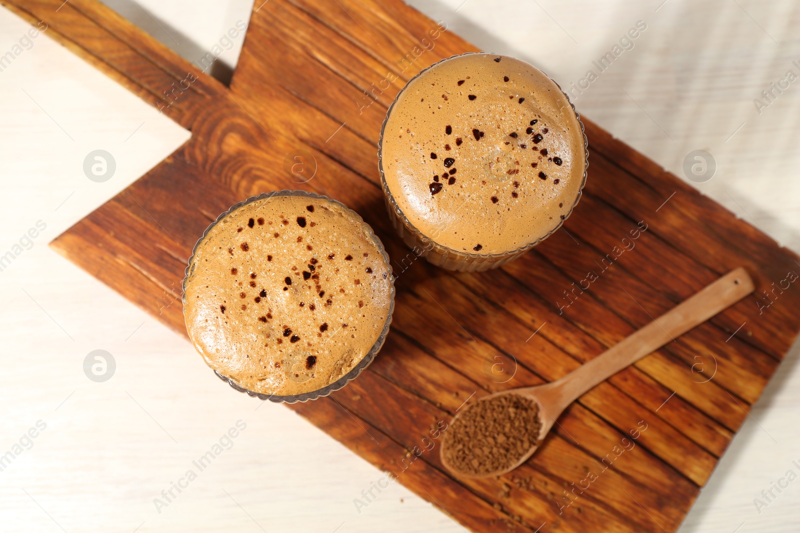 Photo of Delicious dalgona coffee in glasses and granules on light table, top view