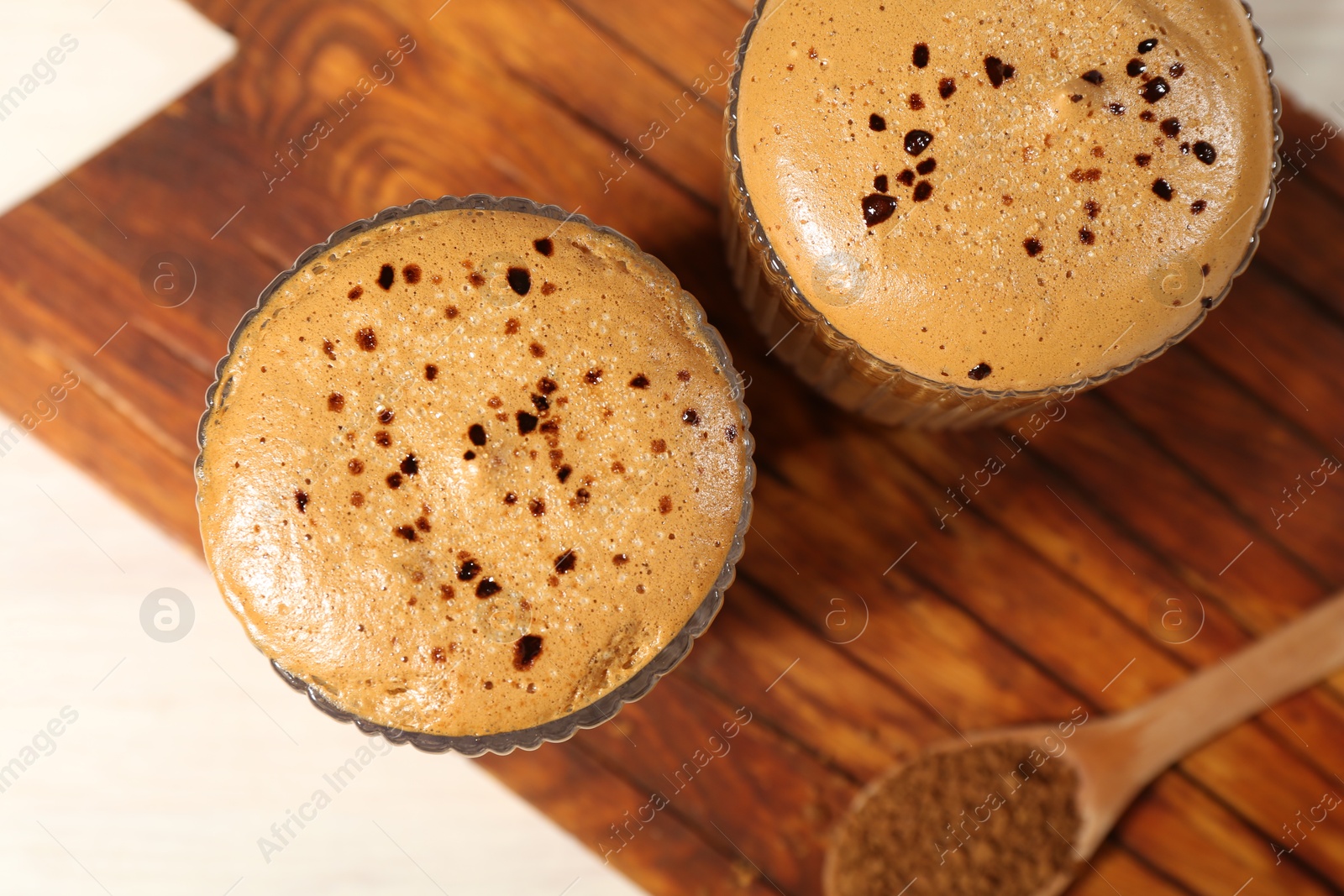 Photo of Delicious dalgona coffee in glasses and granules on light table, top view