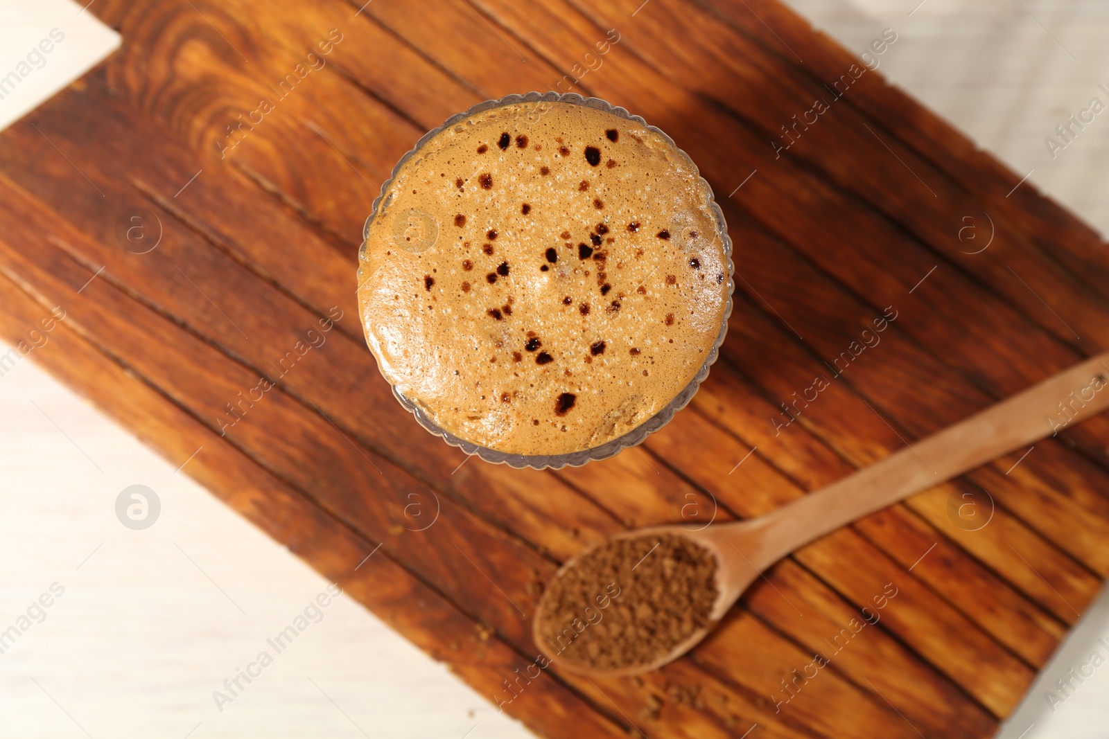 Photo of Delicious dalgona coffee in glass and granules on light table, top view