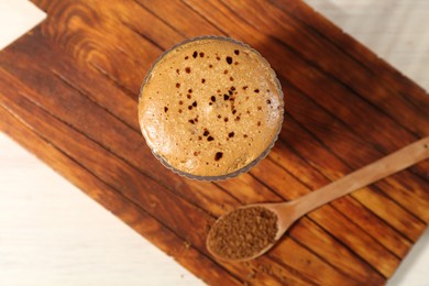 Photo of Delicious dalgona coffee in glass and granules on light table, top view
