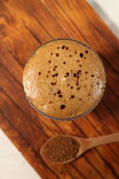 Photo of Delicious dalgona coffee in glass and granules on light table, top view
