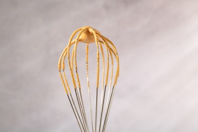 Photo of Making delicious dalgona coffee. Whisk with cream on blurred background, closeup