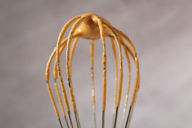 Photo of Making delicious dalgona coffee. Whisk with cream on blurred background, closeup