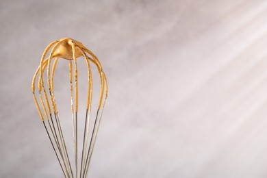 Photo of Making delicious dalgona coffee. Whisk with cream on blurred background, closeup. Space for text