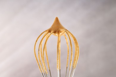 Photo of Making delicious dalgona coffee. Whisk with cream on blurred background, closeup