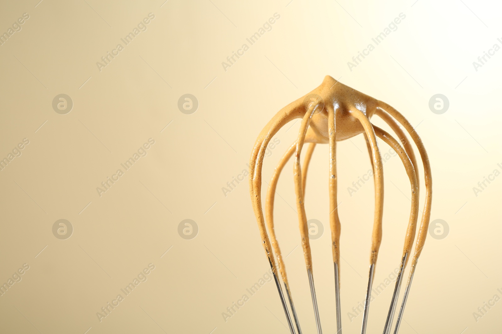 Making delicious dalgona coffee. Whisk with cream on beige background, closeup. Space for text Photo of Making delicious dalgona coffee. Whisk with cream on beige background, closeup. Space for text
