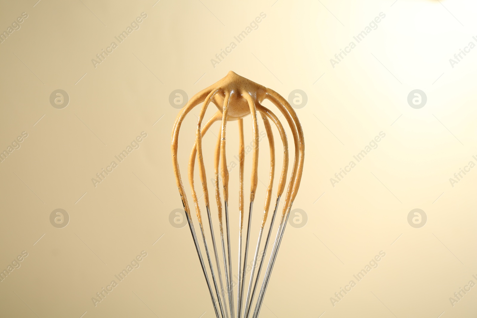 Photo of Making delicious dalgona coffee. Whisk with cream on beige background, closeup