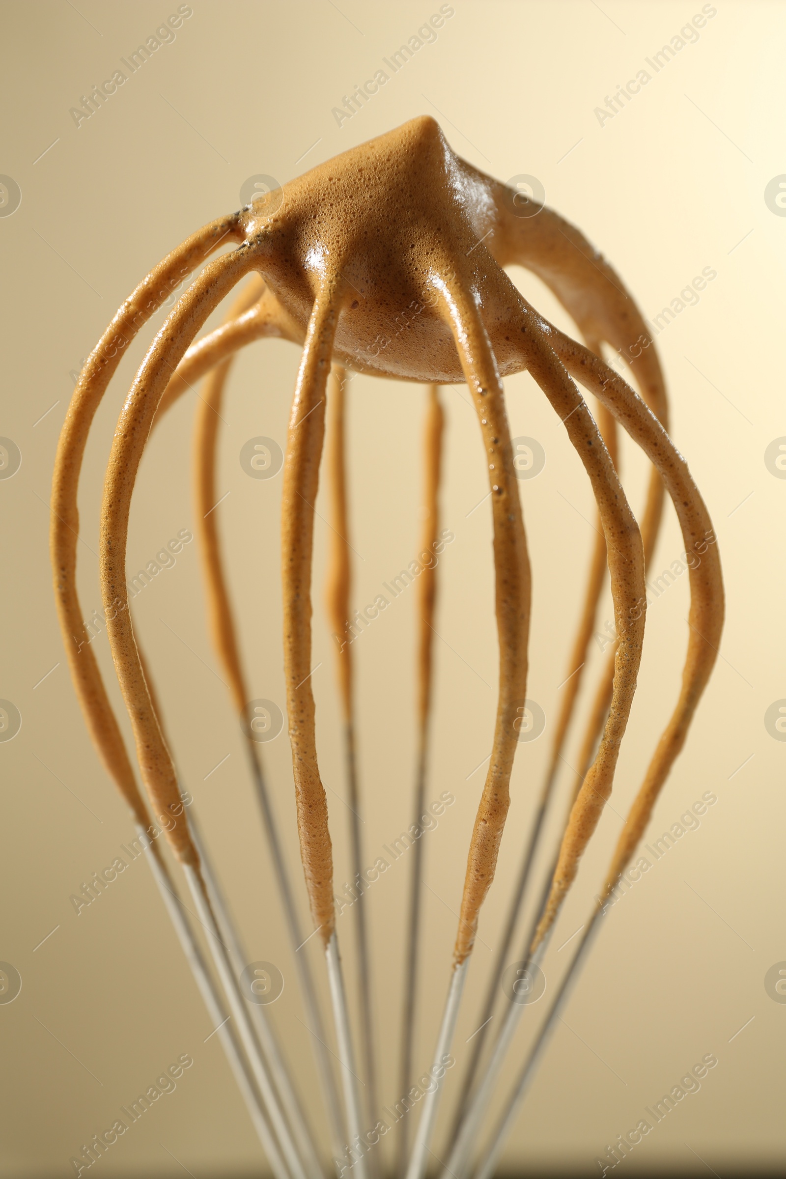 Making delicious dalgona coffee. Whisk with cream on beige background, closeup Photo of Making delicious dalgona coffee. Whisk with cream on beige background, closeup