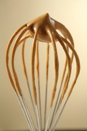 Photo of Making delicious dalgona coffee. Whisk with cream on beige background, closeup