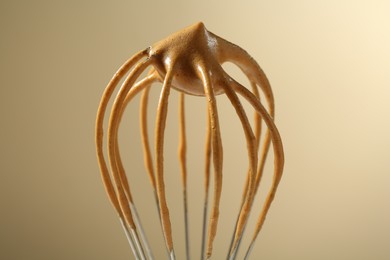 Photo of Making delicious dalgona coffee. Whisk with cream on beige background, closeup