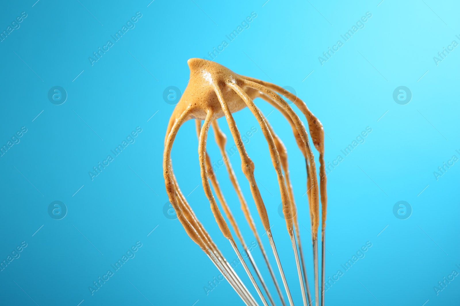 Making delicious dalgona coffee. Whisk with cream on light blue background, closeup Photo of Making delicious dalgona coffee. Whisk with cream on light blue background, closeup