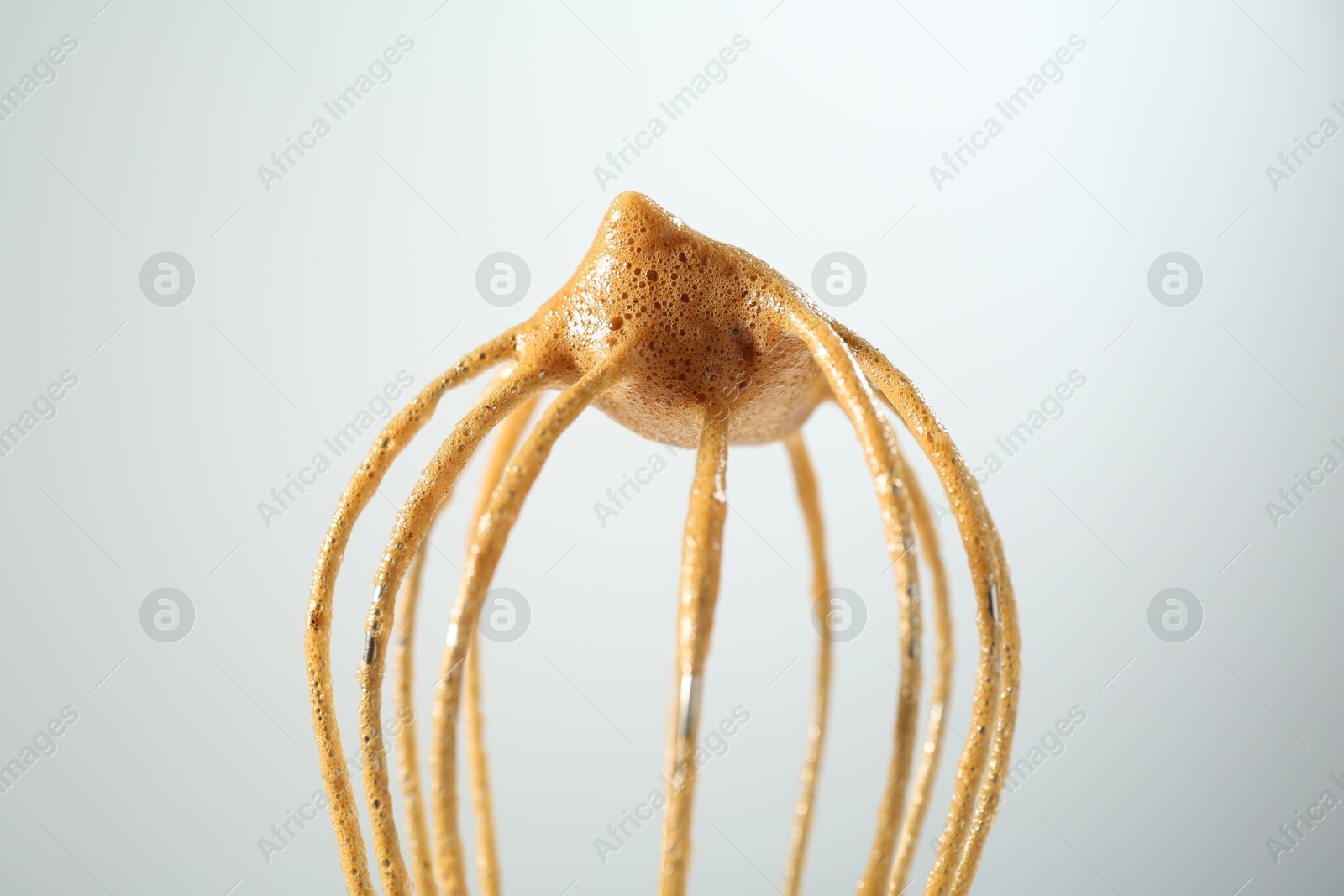 Making delicious dalgona coffee. Whisk with cream on light grey background, closeup Photo of Making delicious dalgona coffee. Whisk with cream on light grey background, closeup